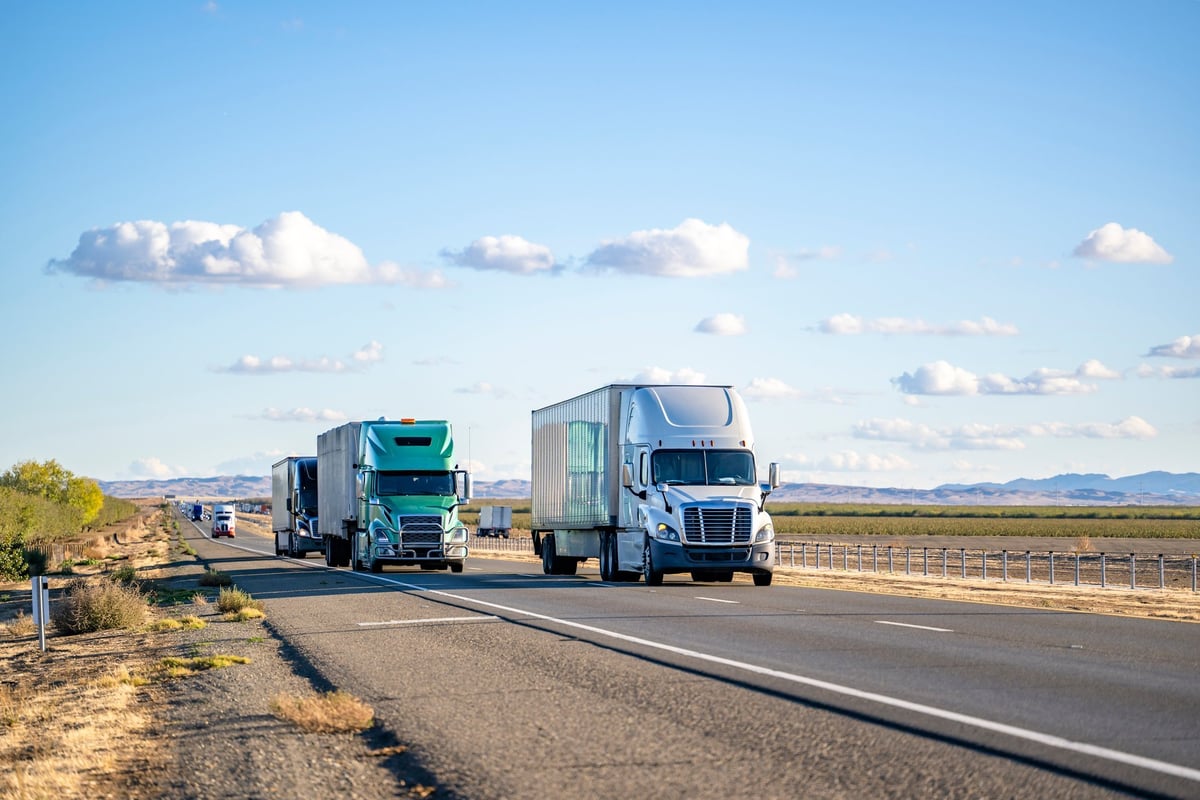 Long-haul semi trucks with trailers traveling a divided highway