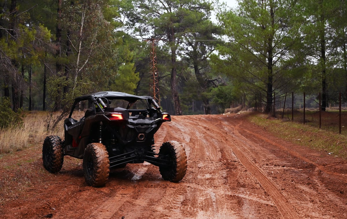 Utility terrain vehicle driving offroad through a forest