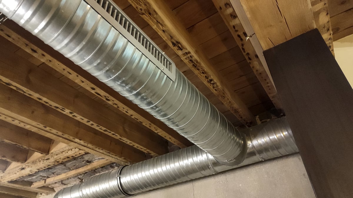 Exposed metal air duct system running across an industrial ceiling