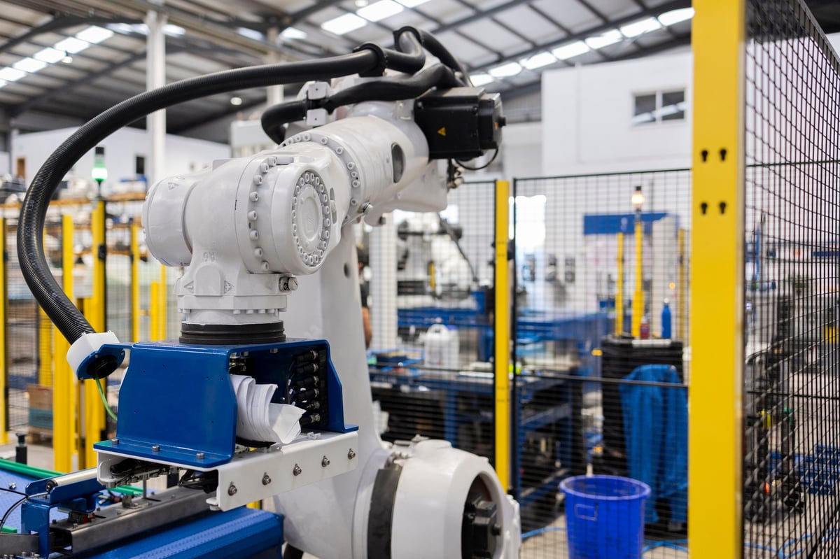 Robotic arm handling material on an automotive assembly line inside a modern factory
