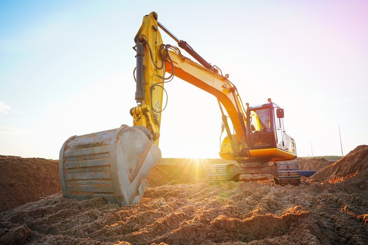Excavator moving soil on a construction site at sunset